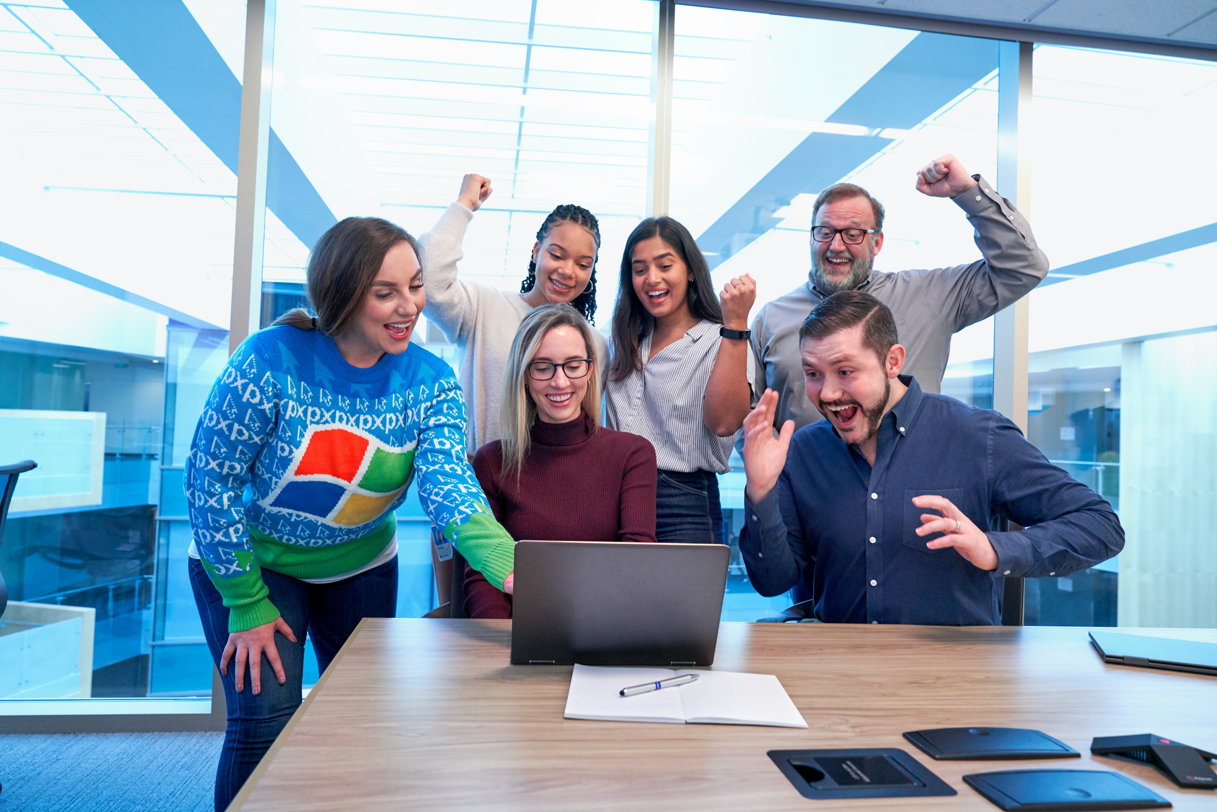 a group of people standing around a laptop computer